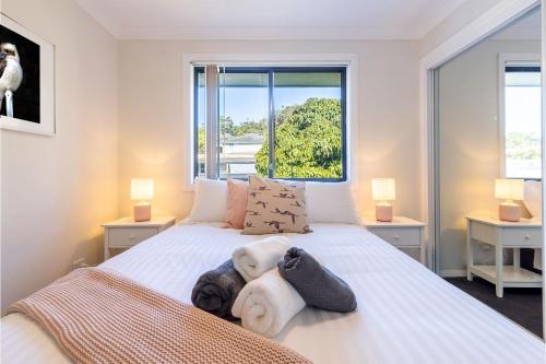 a bedroom with a large white bed with two lamps at Akoya House 122 Tomaree Rd Pet friendly linen air conditioning WiFi and boat parking in Shoal Bay