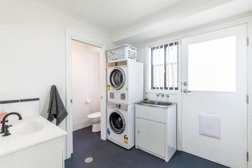 a bathroom with a washing machine and a washer and dryer at Akoya House 122 Tomaree Rd Pet friendly linen air conditioning WiFi and boat parking in Shoal Bay