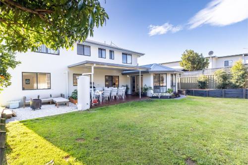 a white house with a lawn in front of it at Akoya House 122 Tomaree Rd Pet friendly linen air conditioning WiFi and boat parking in Shoal Bay