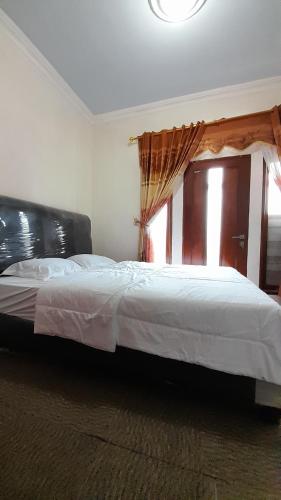 a bedroom with a large bed with a window at Homestay Merpati Dieng Syariah RedPartner in Diyeng