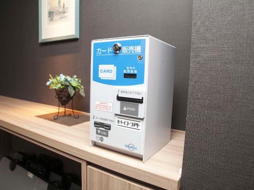 a machine on top of a counter with a vase of flowers at Hotel Route Inn Osaka Izumifuchu in Izumi