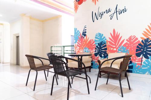 a group of chairs and a table in a room at Wisma Aini Syariah Lampung Mitra RedDoorz in Kedaton