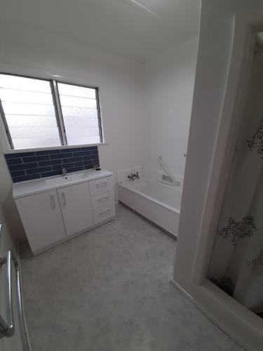 a white bathroom with a tub and a sink at Mary's Place in Opotiki