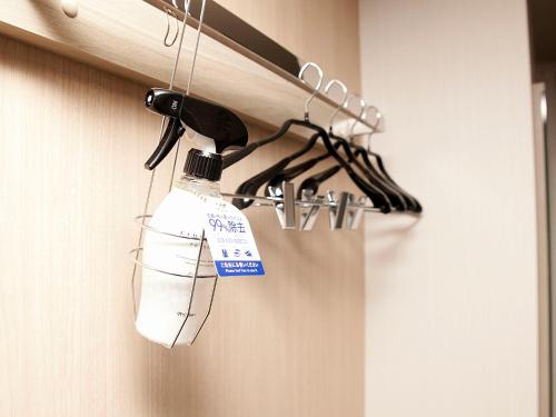 a bottle of bleach hanging from a rack in a bathroom at Hotel Route Inn Matsuyama -Katsuyama Dori- in Matsuyama
