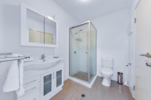 a white bathroom with a shower and a toilet at Candlelight - Airlie Beach in Airlie Beach