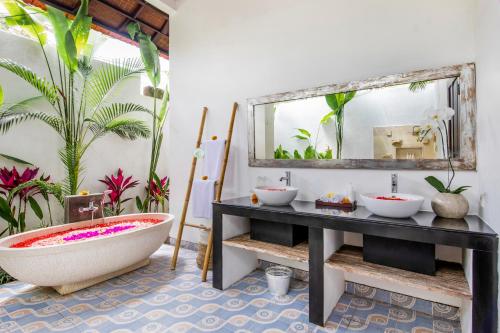a bathroom with a large mirror and a tub at Villa Joyosa in Seminyak