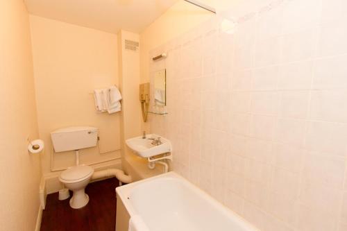 a bathroom with a toilet and a sink and a tub at The Carlton Hotel in Folkestone