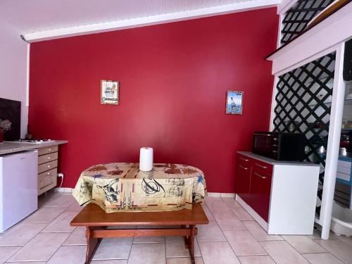 a room with a red wall with a table and a microwave at Appartement de 2 chambres avec jardin clos et wifi a Basse Terre in Basse-Terre