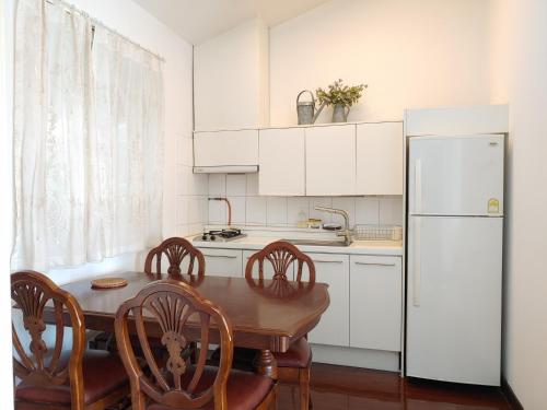 a kitchen with a wooden table and a white refrigerator at Springhill Resort in Seogwipo