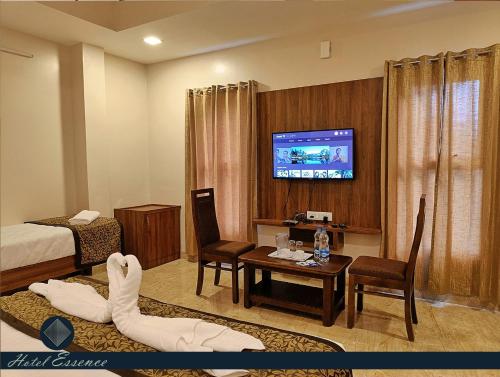 a hotel room with a bed and a table and a tv at Hotel ESSENCE in Vellore