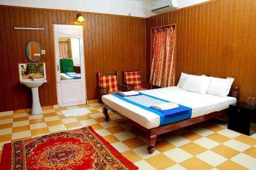 a bedroom with a bed and a bathroom with a sink at Hotel Volga palace in Kovalam