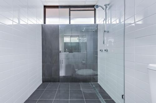 a bathroom with a shower with a toilet and a sink at Central Ocean View Studio 27a in Airlie Beach