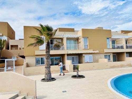 a person walking in front of a building with a palm tree at Bella Vista in Poris de Abona