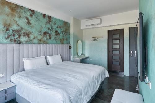- une chambre avec un lit blanc et une peinture murale dans l'établissement 芙蘿拉萃旅, à Taïtung