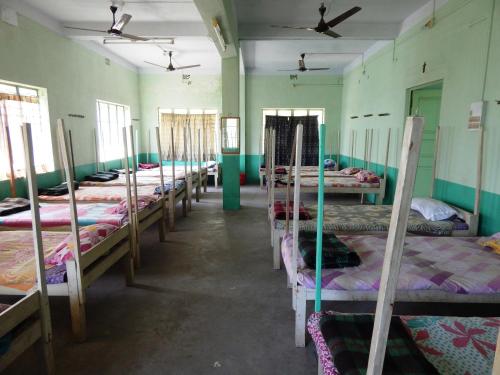 a row of beds in a room with green walls at Seva Kendra Hijli Kharagpur in Kharagpur
