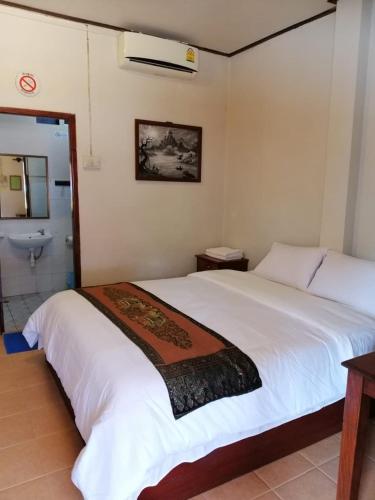 a bedroom with a large white bed and a bathroom at Monsavanh Guesthouse in Pakbeng