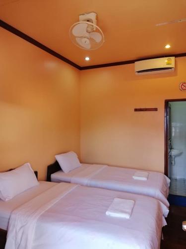 Monsavanh Guesthouse في باكبنج: سريرين في غرفة بجدران برتقالية
