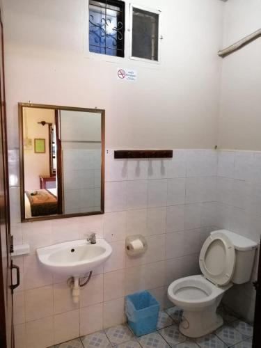 a bathroom with a toilet and a sink and a mirror at Monsavanh Guesthouse in Pakbeng