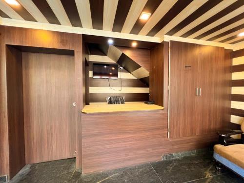 a room with a tv and a wooden wall at Hotel InTourist by Agira Hotel in Bangalore
