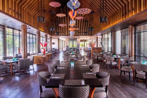 a dining room with tables and chairs and windows at The Sakala Resort Bali All Suites in Nusa Dua