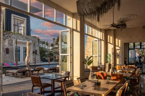a restaurant with tables and chairs and large windows at The Sakala Resort Bali All Suites in Nusa Dua