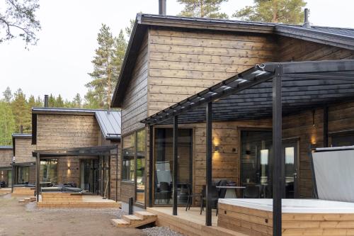 een houten huis met glazen deuren en een patio bij Tykkimäki Resort in Kouvola