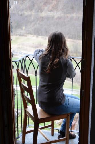 a woman sitting on a chair looking out a window at La Fattoria di Roven in Gignod