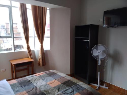 a bedroom with a bed and a fan and a window at Hostal Pacífico Huánuco in Huánuco