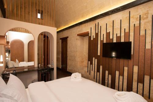 a room with a bed and a tv on a wall at Bayazhan Hotel ve Restaurant in Gaziantep