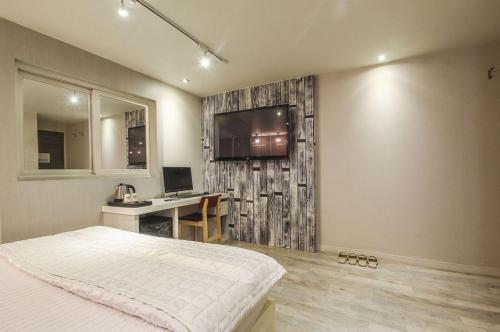 una camera da letto con un letto, una scrivania e una televisione di Cube Hotel a Busan