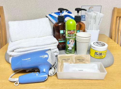 a table with a hair dryer and towels on it at PetitHotel017全室ミニキッチン付きファミリルーム 飲食街中心 阿波踊り会館7分 文理 徳島大学 アスティとくしま車8分 in Tokushima