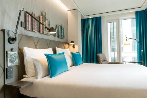 a bedroom with a large white bed with blue pillows at Motel One Manchester-St. Peter´s Square in Manchester