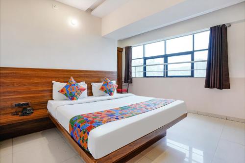 una camera da letto con un grande letto con una grande finestra di FabHotel Paradise Inn a Pune