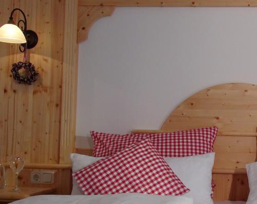 1 dormitorio con 1 cama con almohadas rojas y blancas en Ferienwohnungen Rosenegger, en Staudach-Egerndach