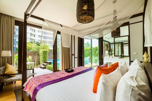 - une chambre avec un grand lit et une grande fenêtre dans l'établissement The Rock Hua Hin Beachfront Spa Resort - SHA Plus, à Hua Hin