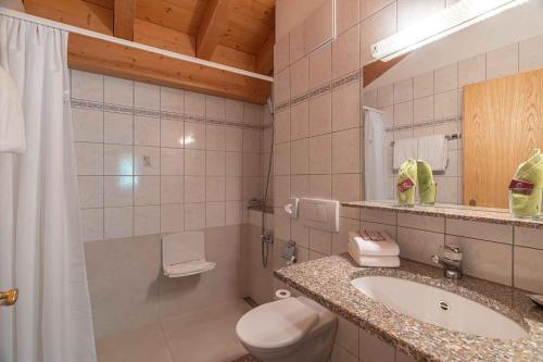 a bathroom with a sink and a toilet and a shower at Aktiv- und Genusshotel Alpenblick in Fiesch