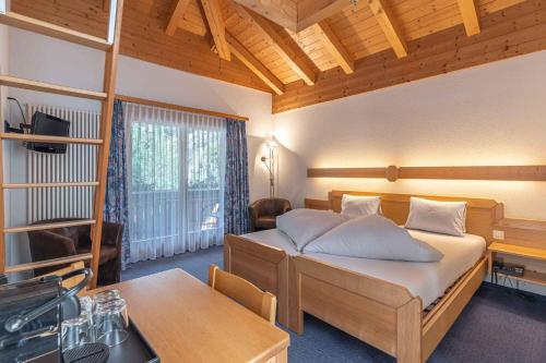 a bedroom with a bed and a table in it at Aktiv- und Genusshotel Alpenblick in Fiesch