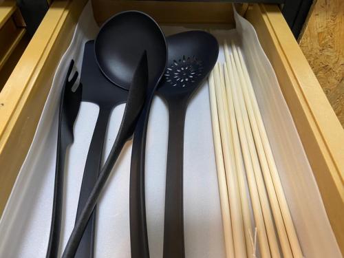 three black plastic spoons in a drawer at 東神楽大学ゲストハウス in Higashikagura