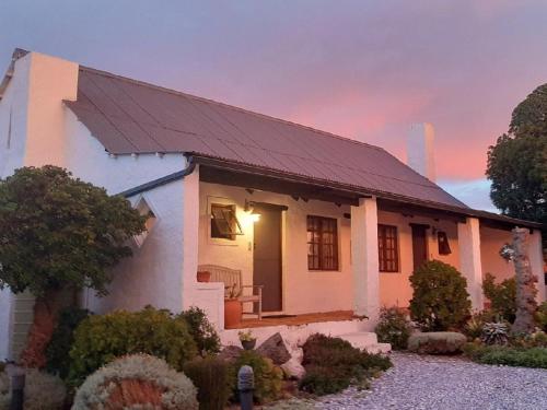 una pequeña casa blanca con techo solar en Kaijaiki Country Inn and Restaurant, en Yzerfontein
