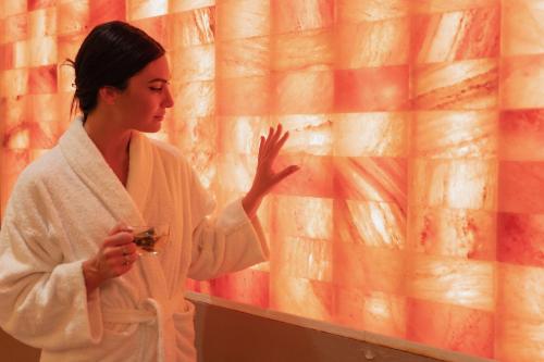 a woman in a white robe standing in front of a wall at San Michele Relais & Spa in Sirolo