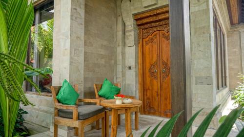 a patio with a table and chairs and a wooden door at Sakti Garden Resort & Spa in Ubud