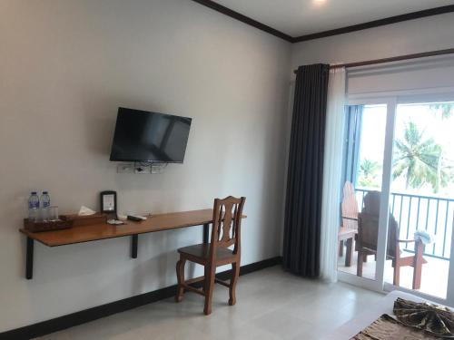 a room with a desk and a television on a wall at Koh Yao Yai Sea Breeze House เกาะยาวใหญ่ซีบรีซเฮ้าส์ in Ko Yao Yai