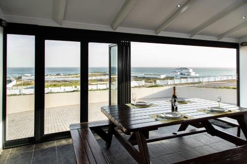 a dining room with a table and a view of the ocean at Pearl Haven, coastal comfort just steps from the shore! in Yzerfontein