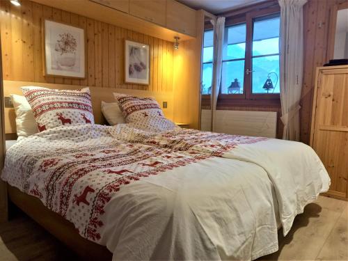 ein Schlafzimmer mit einem großen Bett mit Kissen und einem Fenster in der Unterkunft Le Sapin in Les Diablerets