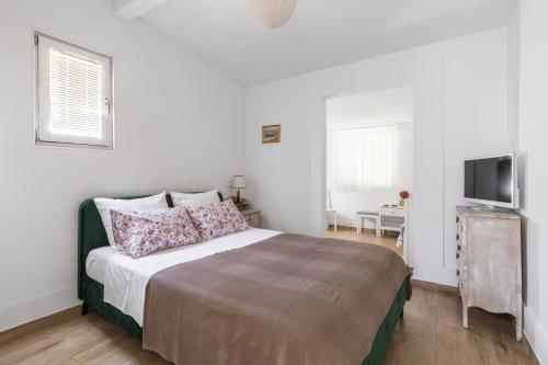 a white bedroom with a bed and a television at Holiday Home Split in Split