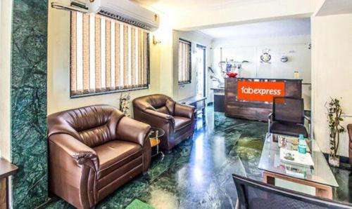 a living room with two leather chairs and a television at FabHotel East Field Homes in Pune