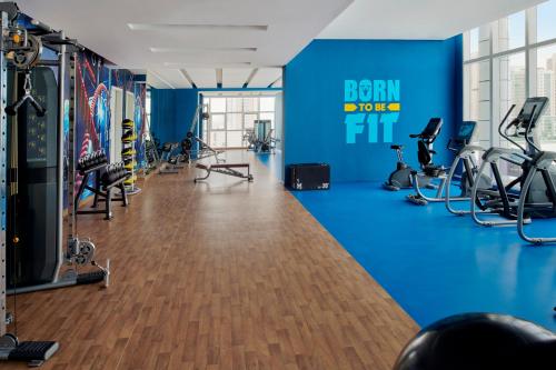 a gym with exercise equipment and a blue wall at Movenpick Jumeirah Village Triangle in Dubai