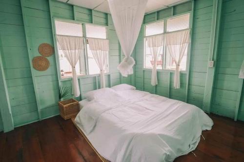 a green room with a bed and two windows at Popole in Nonthaburi
