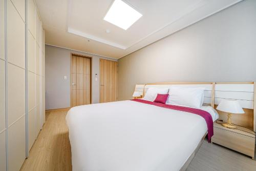 a bedroom with a large white bed and a skylight at EdenStay in Geoje 