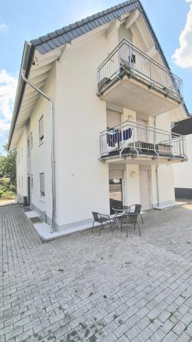 a white building with two chairs and a balcony at Overath Luxus Apartments nähe Köln City/Messe in Overath